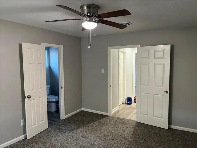 an empty room with closet and a chandelier fan