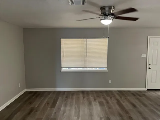 an empty room with a window and a fan