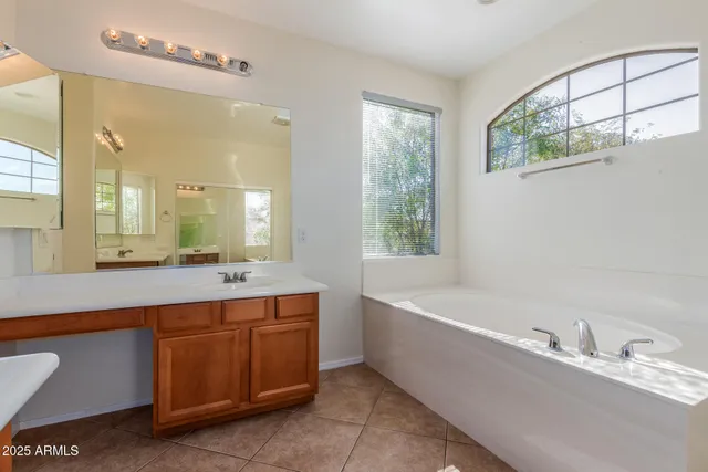 a spacious bathroom with a tub sink and mirror