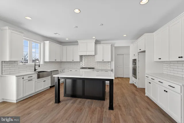 a kitchen with white cabinets stove and sink