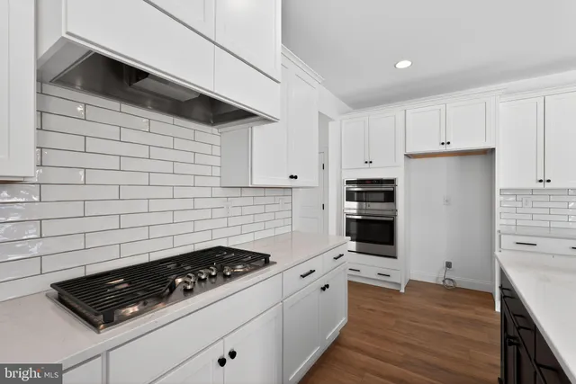 a kitchen with granite countertop a stove and a wooden floor