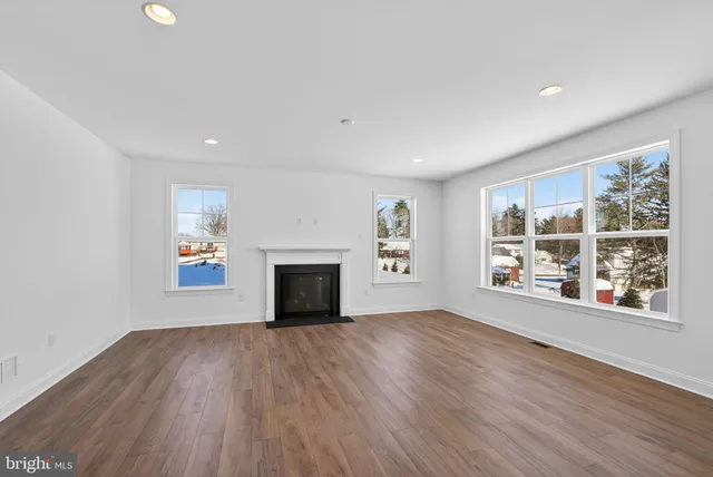 an empty room with windows fireplace and wooden floor