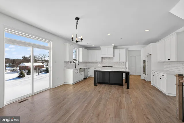 a large kitchen with stainless steel appliances kitchen island granite countertop a large cabinets a sink and wooden floor