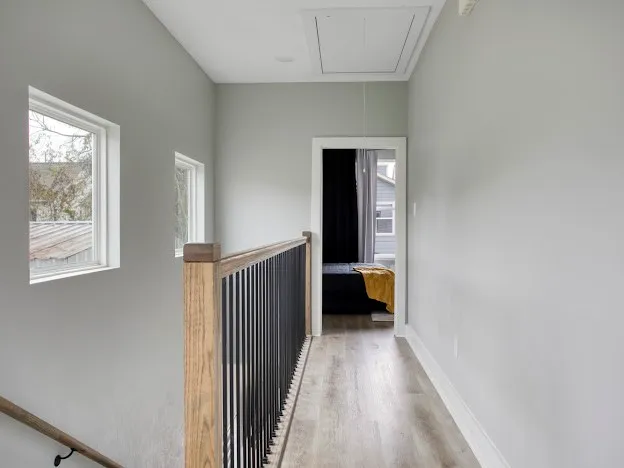 a view of a hallway with wooden floor and a bathroom