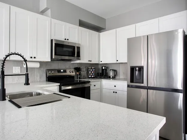 a kitchen with granite countertop white cabinets and stainless steel appliances