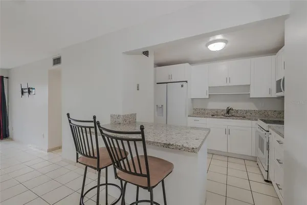 a kitchen with stainless steel appliances granite countertop a table and chairs in it