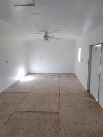 an empty room with a ceiling fan and bathroom view