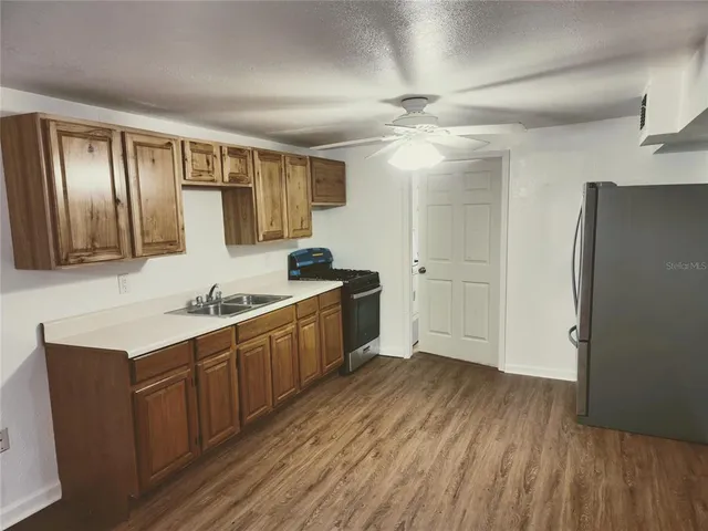 a kitchen with granite countertop a refrigerator a sink and wooden cabinets