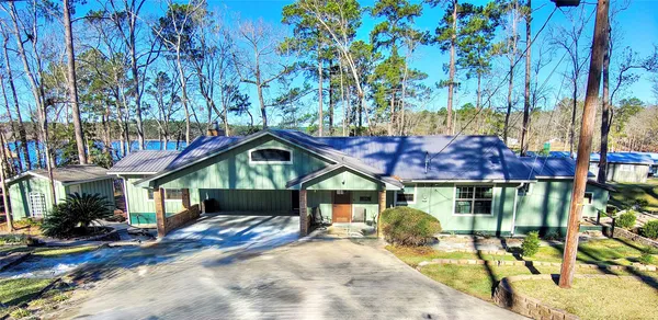 a front view of a house with a yard outdoor seating and covered with trees