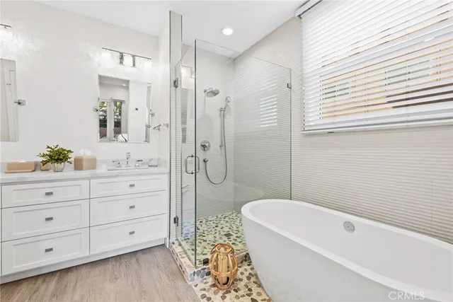 a bathroom with a granite countertop sink a mirror a bathtub and shower
