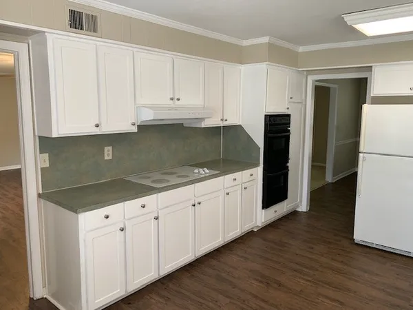 a kitchen with granite countertop white cabinets and refrigerator