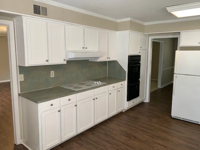 a kitchen with granite countertop white cabinets and refrigerator