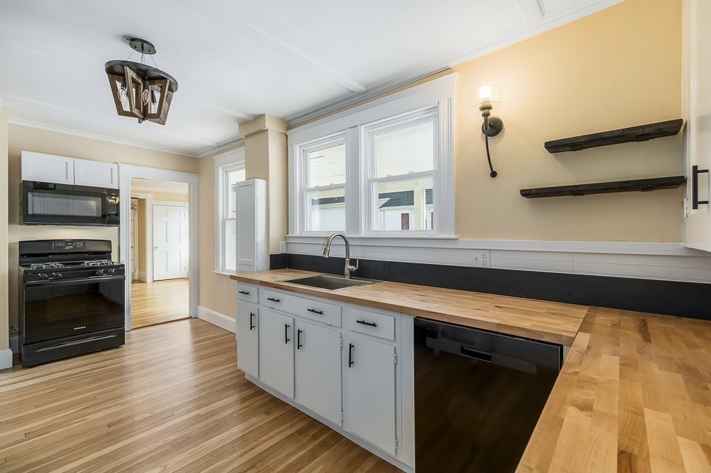 13 Washington Street, Unit 2 Beverly, MA 01915 - Photo 7 of 14 a large kitchen with stainless steel appliances a large counter top a stove and a refrigerator