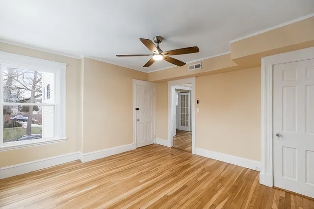 a view of empty room with wooden floor and fan