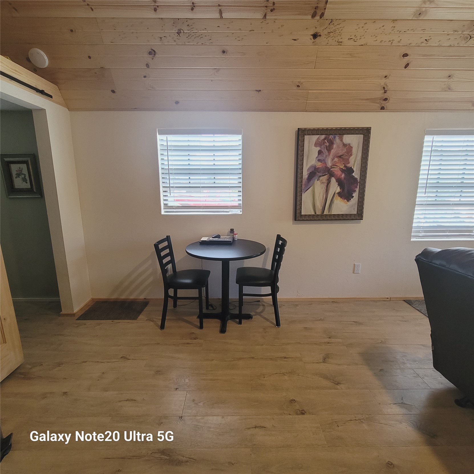 115 Locust Road Stigler, OK 74462 - Photo 19 of 29 Wood-finish flooring, two windows with blinds, a wood plank ceiling, and a wall-mounted light fixture