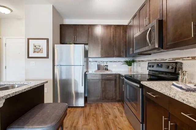 a kitchen with stainless steel appliances granite countertop a sink refrigerator and cabinets