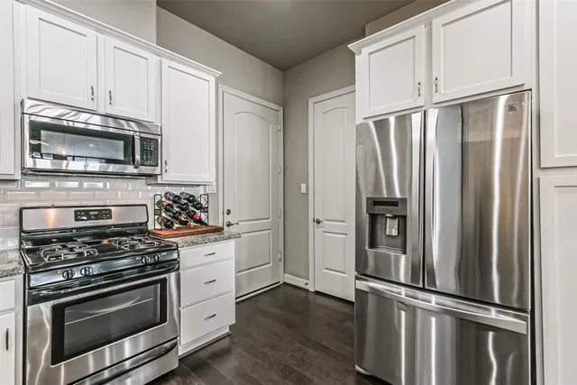 a kitchen with cabinets stainless steel appliances and wooden floor