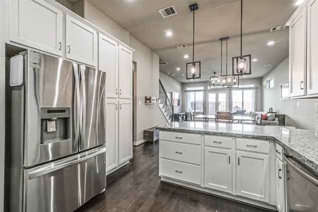 a kitchen with granite countertop a refrigerator and countertop cabinets