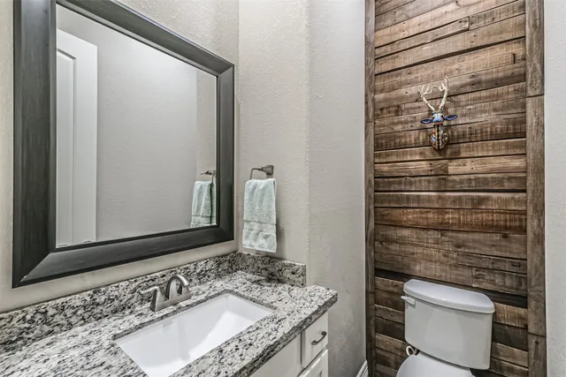 a bathroom with a granite countertop sink and a toilet