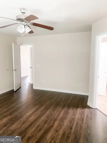an empty room with wooden floor fan and windows