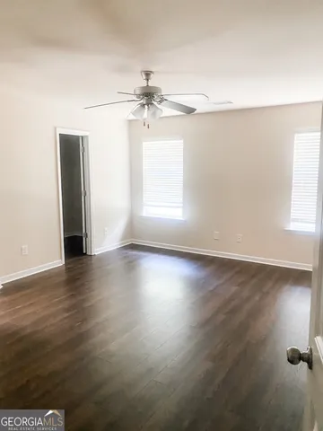 an empty room with wooden floor chandelier fan and windows