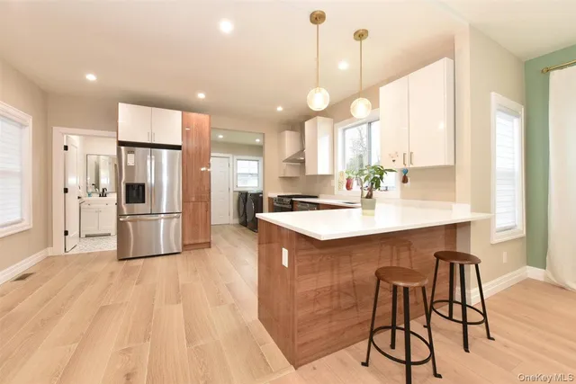 a kitchen with stainless steel appliances granite countertop a sink a stove a refrigerator and island with wooden floor