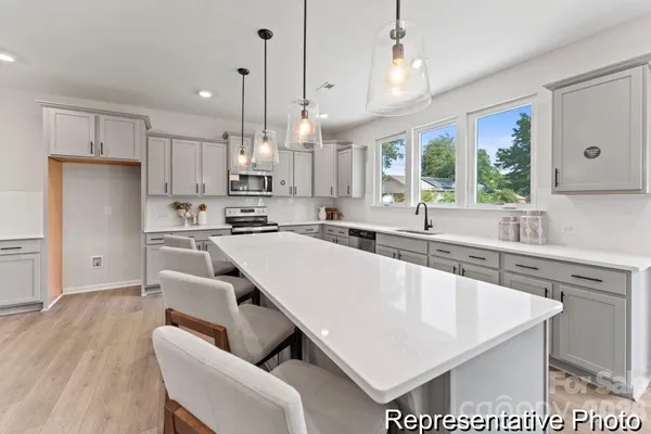 a large kitchen with cabinets a sink a center island stainless steel appliances and a window