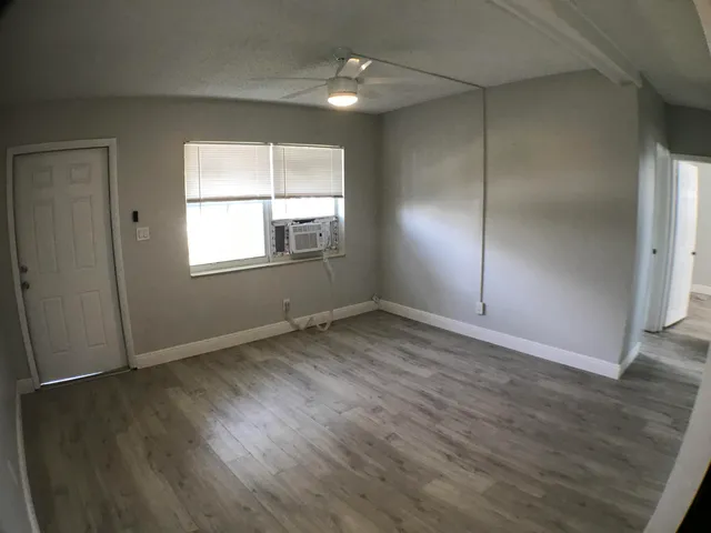 an empty room with wooden floor and fan