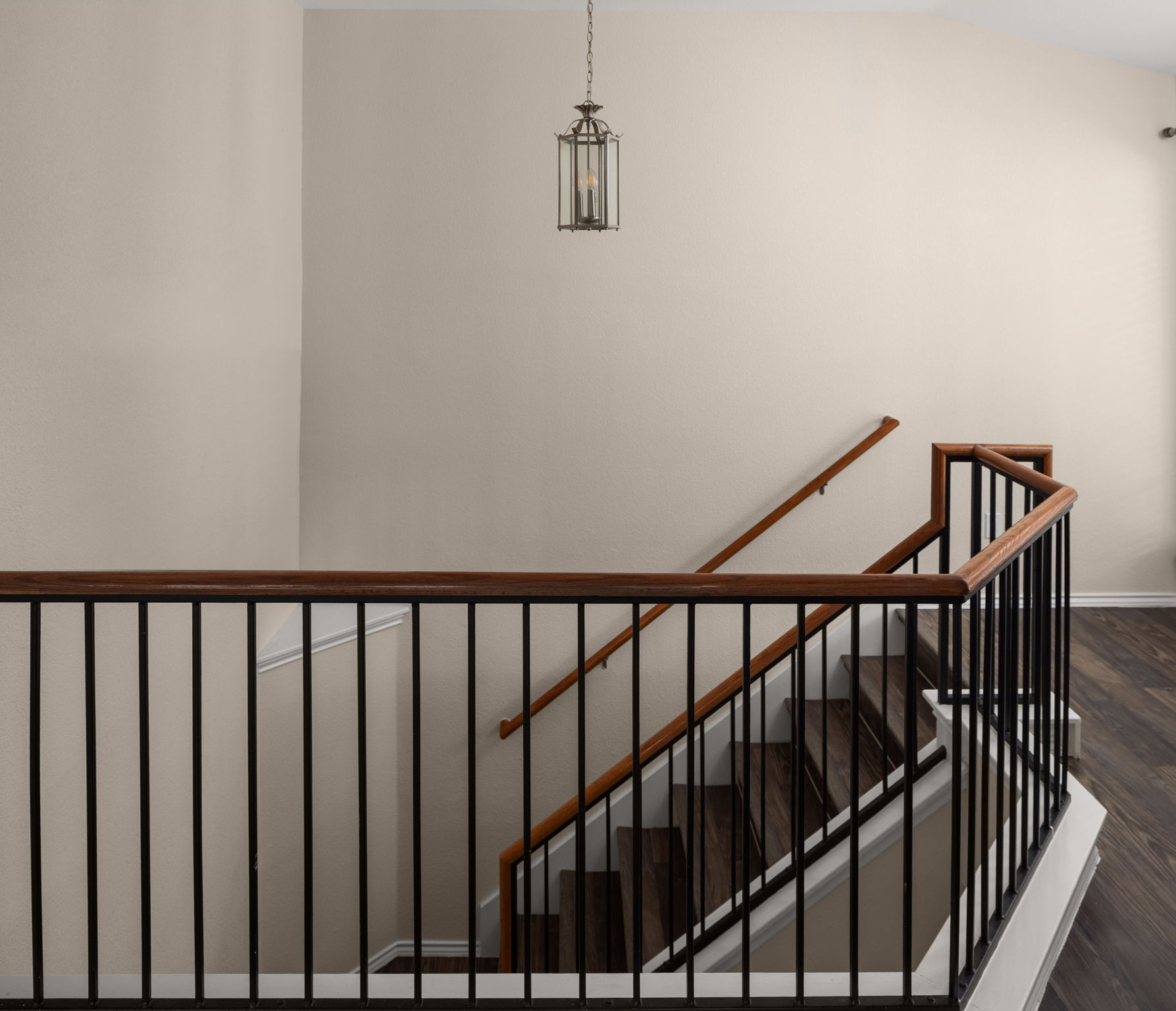 14815 Avery Ranch Boulevard, Unit 1401 Austin, TX 78717 - Photo 21 of 38 Staircase featuring dark wood-finish flooring, wrought iron spindles, a rich wood handrail, and a hanging lantern-style light fixture