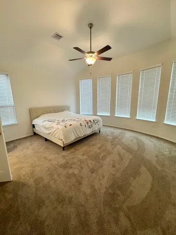 a spacious bedroom with a bed and a ceiling fan