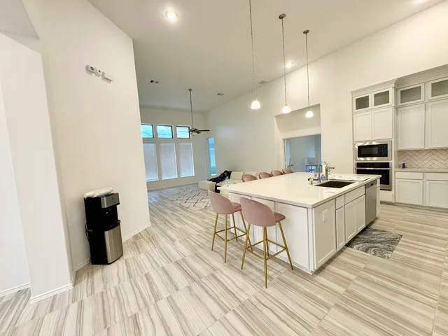 a large white kitchen with a sink and wooden floor