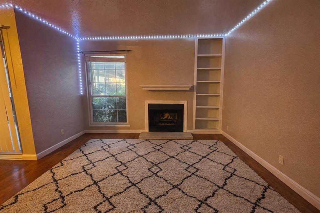 a view of an empty room with a fireplace and a window
