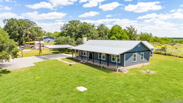 a view of a house with a big yard and large trees