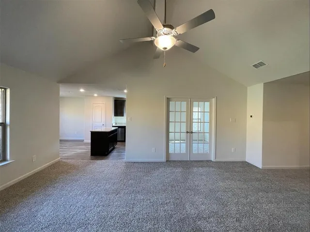 an empty room with windows and ceiling fan