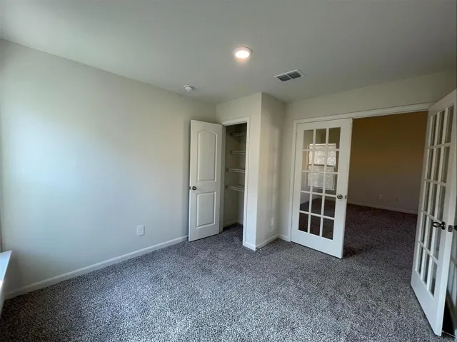 an empty room with closet and windows