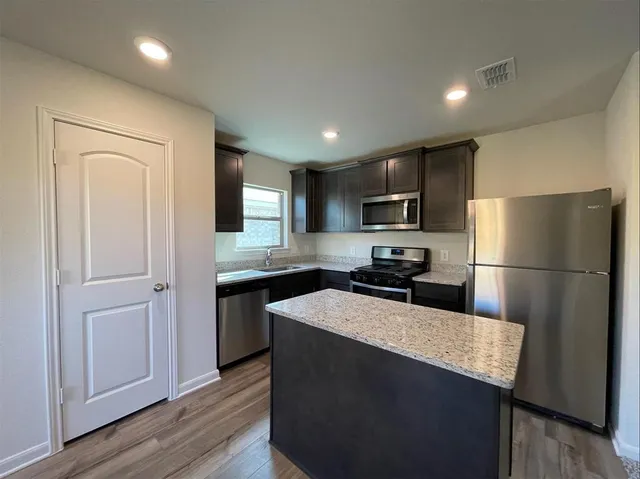 a kitchen with a refrigerator a microwave a sink and cabinets