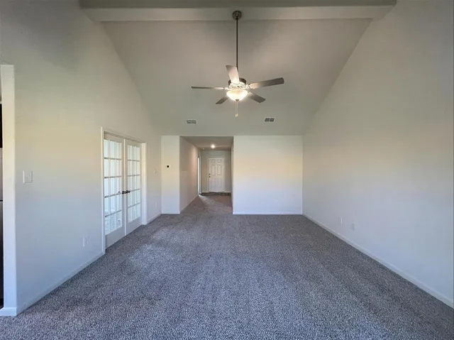 an empty room with chandelier fan and windows