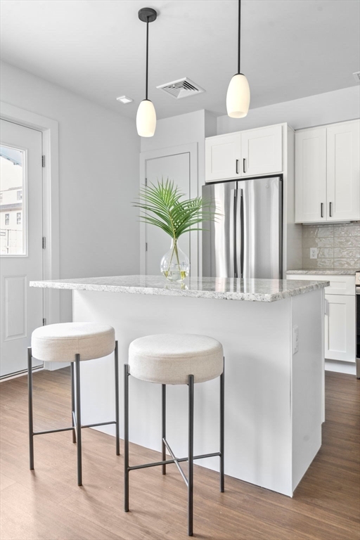 3 B Wilson Street, Unit 3B Natick, MA 01760 - Photo 10 of 33 a kitchen with stainless steel appliances granite countertop a table chairs and white cabinets