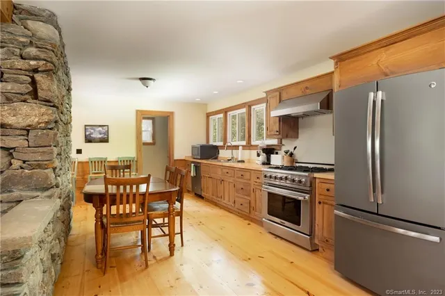 a kitchen with stainless steel appliances granite countertop a stove a refrigerator a dining table and chairs with wooden floor