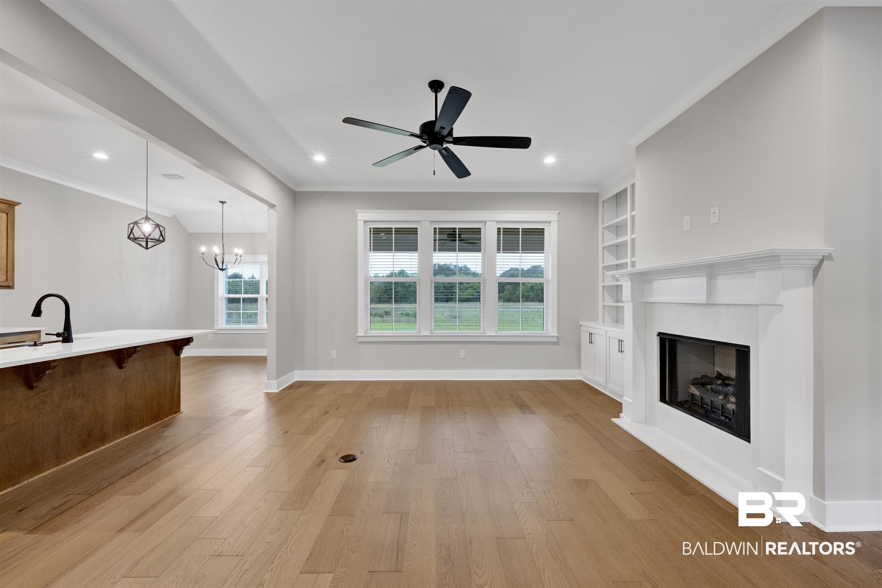 27371 Patch Pl Loop Daphne, AL 36526 - Photo 27 of 63 Spacious interior featuring wood-finish flooring, a white mantel fireplace with built-in shelving, multi-pane windows, recessed lighting, and a contemporary ceiling fan