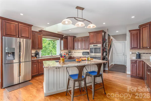 a kitchen with stainless steel appliances a dining table chairs refrigerator and cabinets