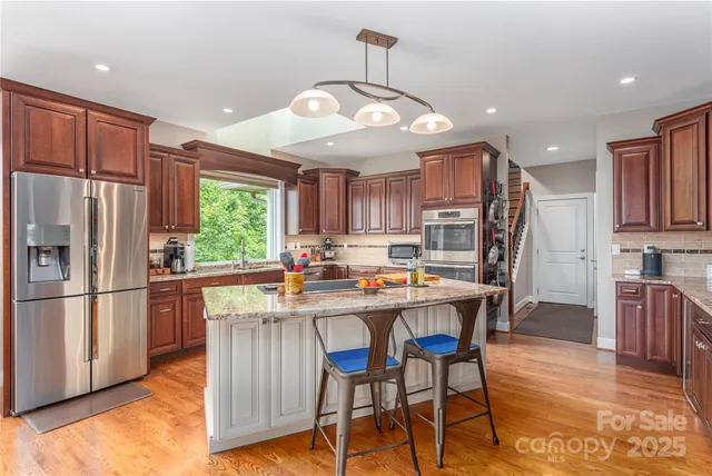 a kitchen with stainless steel appliances a dining table chairs refrigerator and microwave