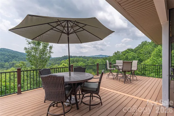 a view of a roof deck with table and chairs under an umbrella with wooden floor