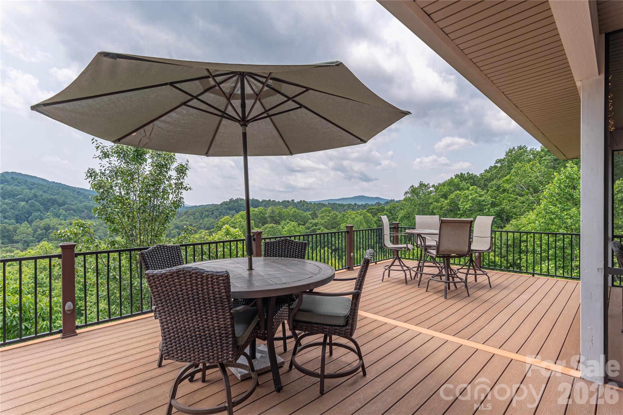 930 Big Raven Lane Saluda, NC 28773 - Photo 4 of 35 a view of a roof deck with table and chairs under an umbrella with wooden floor