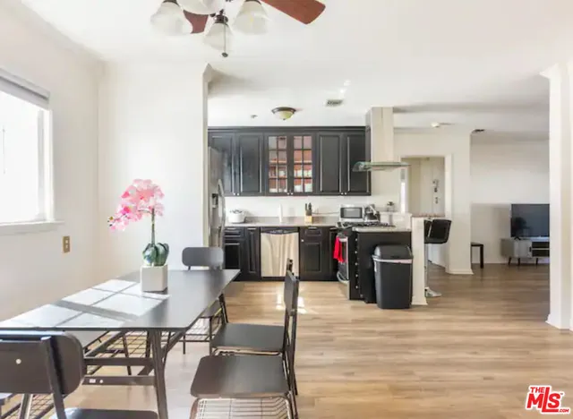 a living room with stainless steel appliances kitchen island granite countertop a table chairs and a refrigerator