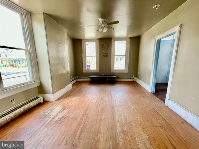 a view of an empty room with a window and wooden floor