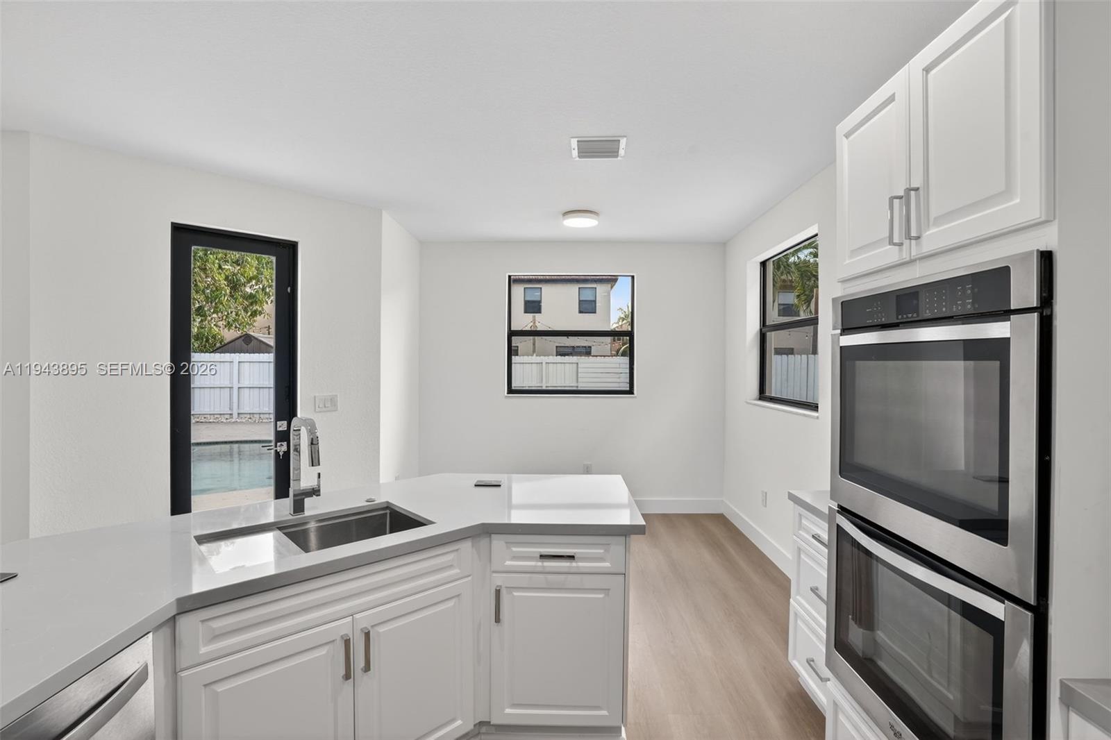 11556 Southwest 234th Street Homestead, FL 33032 - Photo 15 of 44 a kitchen with stainless steel appliances white cabinets and a wooden floor