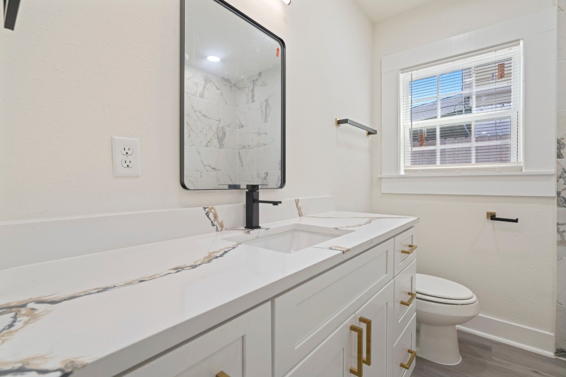 2817 Winbern Street Houston, TX 77004 - Photo 10 of 23 a bathroom with a granite countertop sink a toilet and a mirror