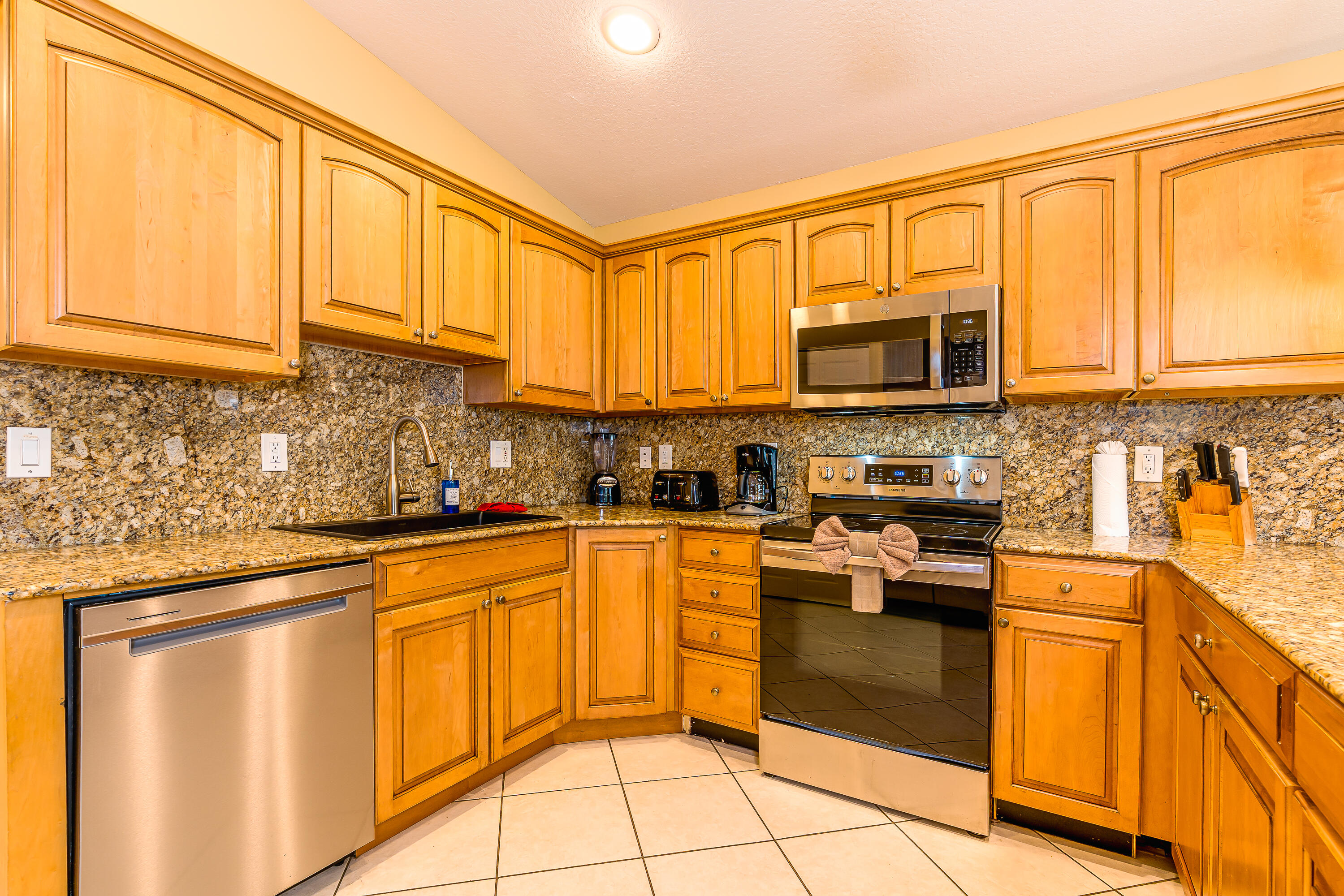 260 Sadowski Causeway Key Colony Beach, FL 33051 - Photo 5 of 50 a kitchen with stainless steel appliances granite countertop a stove top oven a sink dishwasher and white cabinets with wooden floor