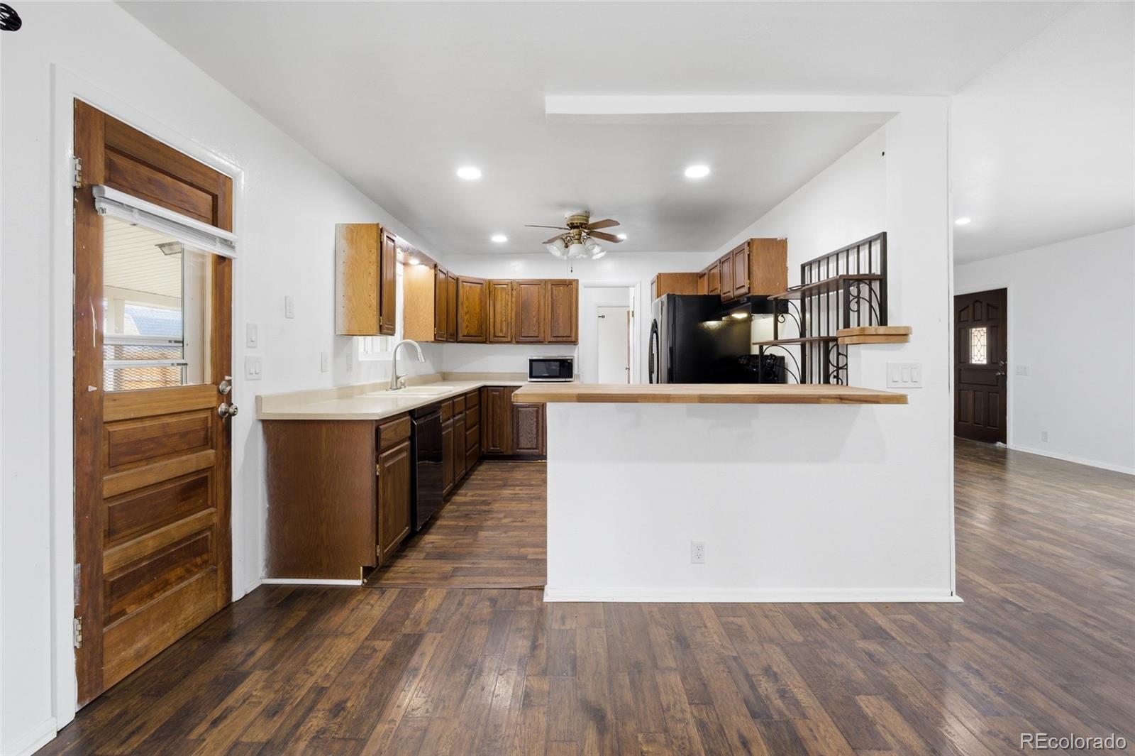 308 Fifth Street Dacono, CO 80514 - Photo 12 of 29 a large kitchen with a center island and wooden floor